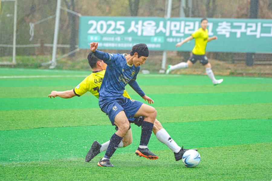 빗속 경기에서 상대와 볼 경합하는 모습